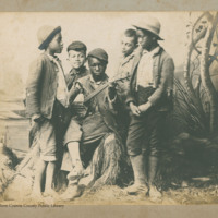Five African American boys in studio scene, one playing banjo